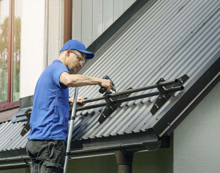 roofer installing snow guard on metal roof